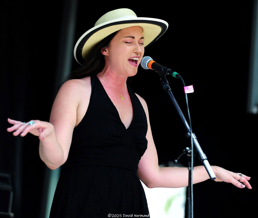 Sariah Sizemore mid-song with arms open, wearing a straw hat and black dress