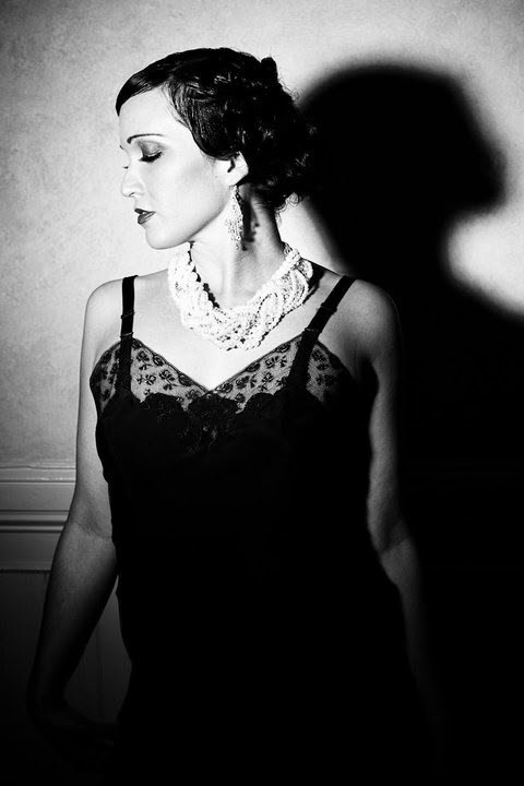 Sariah Sizemore in profile in a black lace dress and beaded collar, styled in 1920s fashion