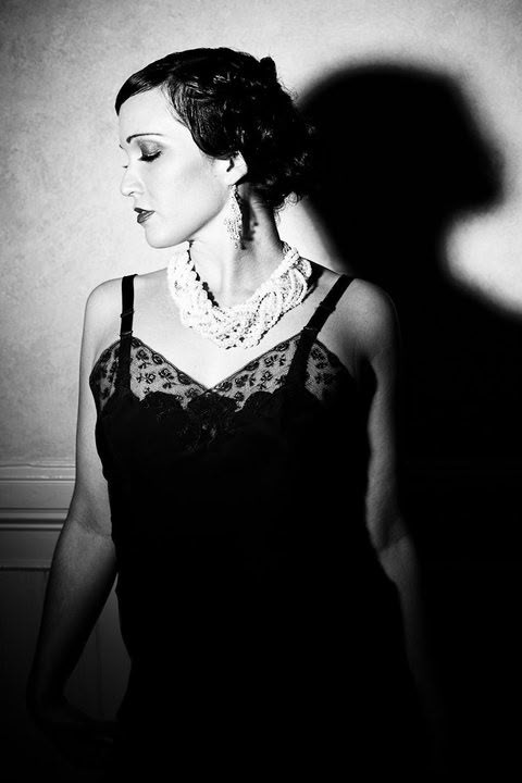 Sariah Sizemore in profile in a black lace dress and beaded collar, styled in 1920s fashion
