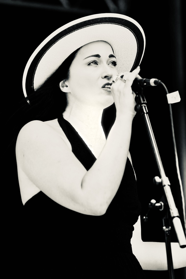 Sariah Sizemore singing into a microphone in a wide-brimmed hat